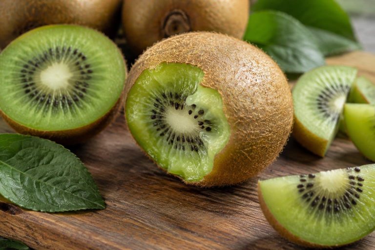 Gros plan photoréaliste d'un kiwi entier avec la peau, présentant une morsure visible qui révèle la chair verte juteuse, posé sur une planche en bois.